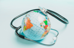 A stethoscope wrapped around a globe, symbolizing global health and healthcare worldwide, on a light blue background.