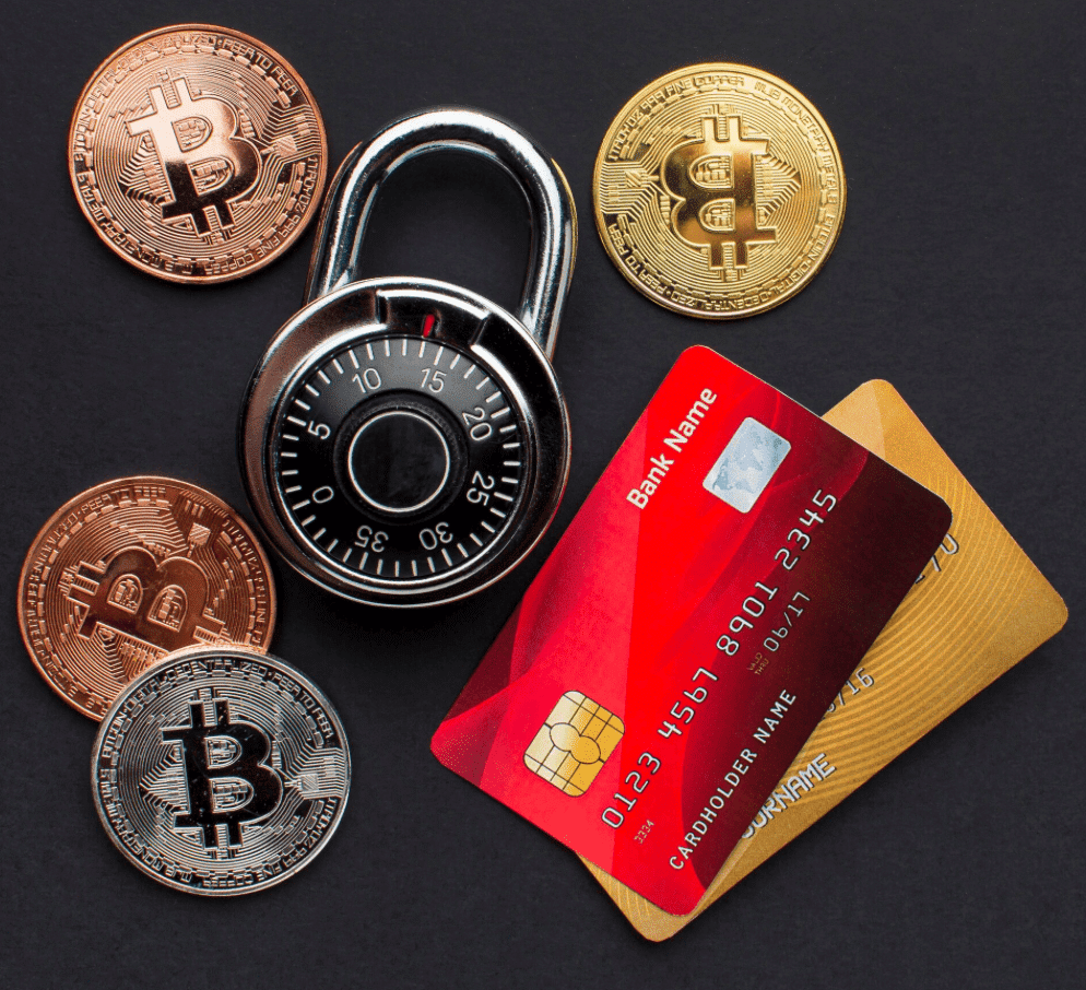 A combination padlock, several Bitcoin coins, and two credit cards are arranged on a dark surface, symbolizing digital security and financial protection.